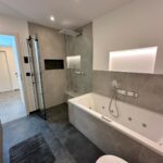 Ein modernes, grau gefliestes Bad mit barrierefreier Dusche