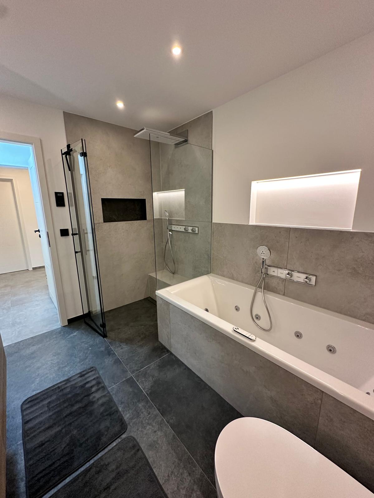Ein modernes, grau gefliestes Bad mit barrierefreier Dusche